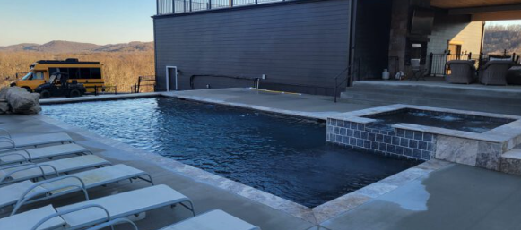 Modern dark-finish gunite pool with attached spa and travertine coping